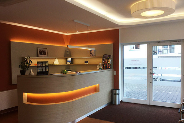 Moderne Arztpraxis mit beleuchtetem Empfangstresen und heller Wartebereich-Atmosphäre.